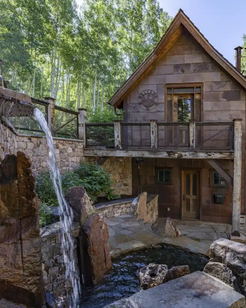 Telluride area home with water feature in the foreground and summer aspens in the background.