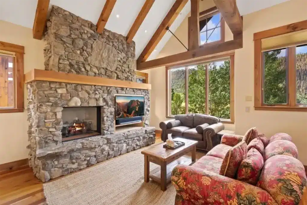 Shimkonis Partners Telluride real estate listing, 210 S Sunset Ridge, bright, airy interior living space with verdant, summer views and fireplace