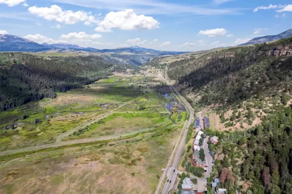 Shimkonis Partners Telluride real estate listing, 210 S Sunset Ridge, aerial summer view of home, highway and the valley floor