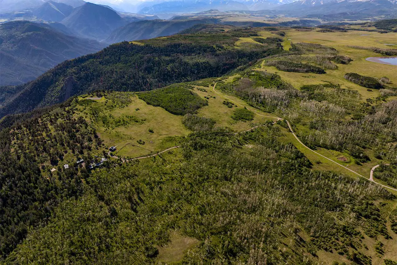Shimkonis Partners Telluride area real estate listing, Laughing Dog Ranch: a rare 243-acre sanctuary, summer blue-sky aerial view with lakes, buildings, road and canyon beyond