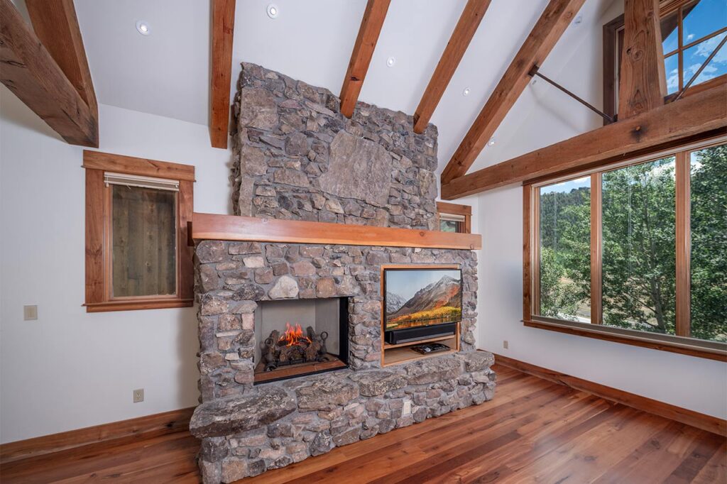 Shimkonis Partners Telluride real estate listing, 210 S Sunset Ridge, bright, airy interior living space with fireplace and verdant, summer views